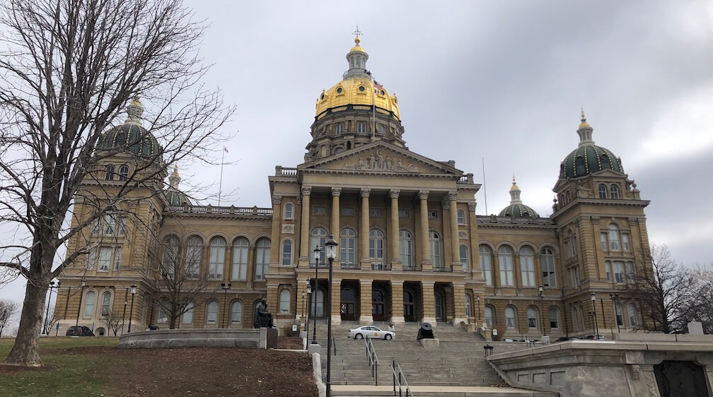 The Iowa Capitol building from the front with a cloudy sky