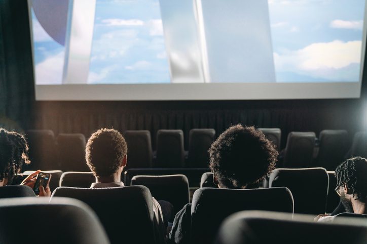 Rear view of people watching a movie at the movie theatre.