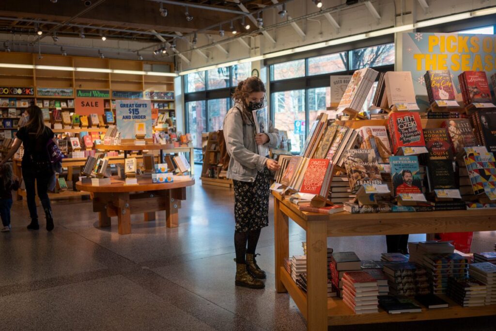 A masked customer browses the books on display in the Powell's City of Books store, the headquarters of Powell's in Portland, Oregon, during the COVID pandemic.