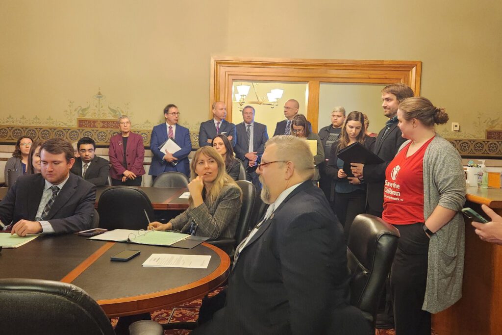 In the subcommittee room for a bill to fund a healthy food program, a crowd of people fills the frame, Sens. Sarah Trone Garriott and Mike Klimesh are seated at the table.